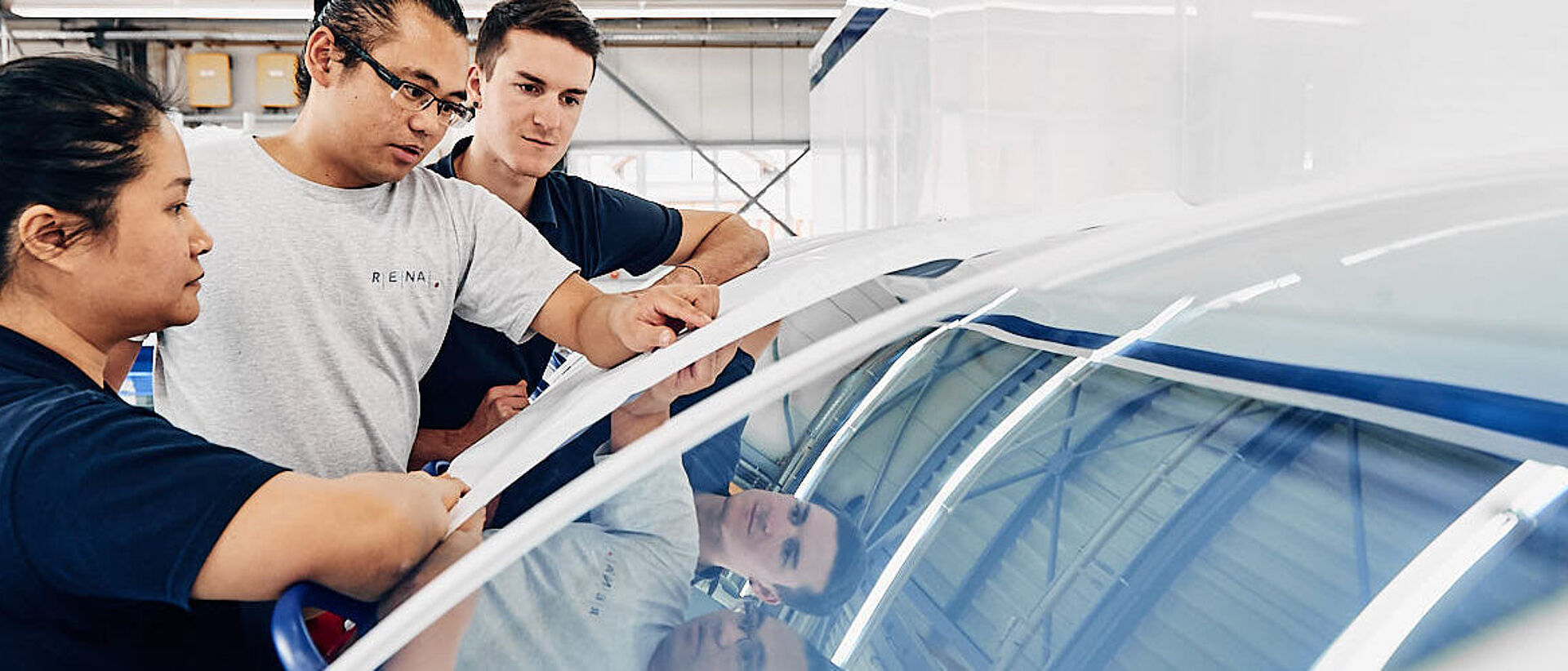 three RENA employees leaning over automized wet-chemical RENA machine